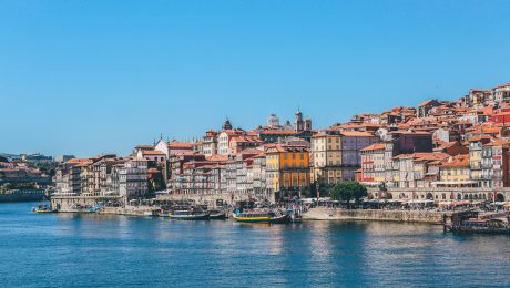 Wide shot of boats on the body of water near houses and buildings in Porto, Portugal